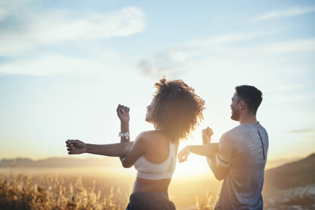 shot of a young couple stretching while out for a workout on a mountain road